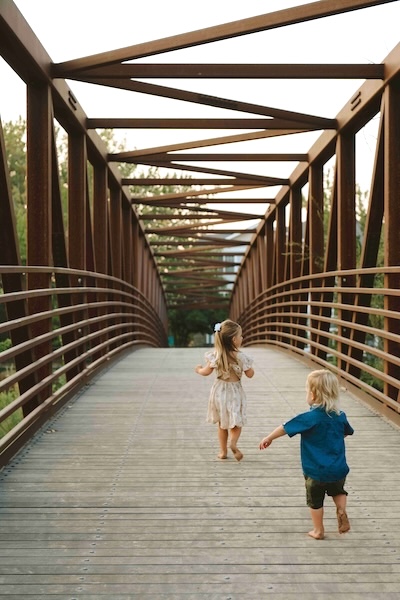 little girl and boy on bridge